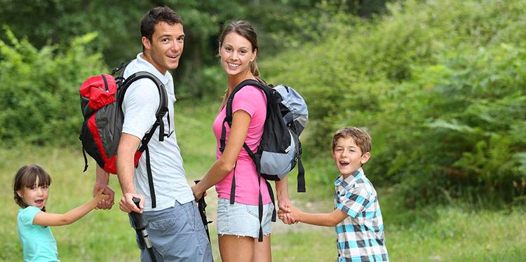 image of couple walking through a field while holding their children. They look into each others eyes and acknowledge that they have the best Life insurance located in Bartlett, TN